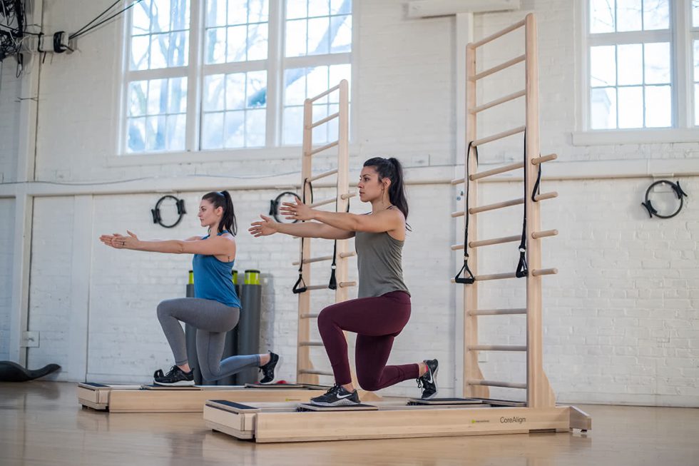 Two women exercising on CoreAlign with ladder in a studio.