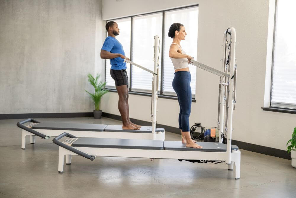 Two people using the Allegro 2 Tower of Power in a Pilates studio.