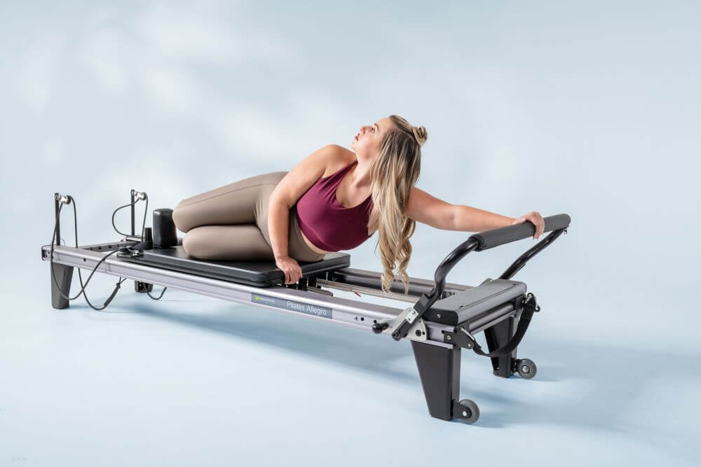 Woman performing Pilates on Allegro Reformer for Balanced Body.