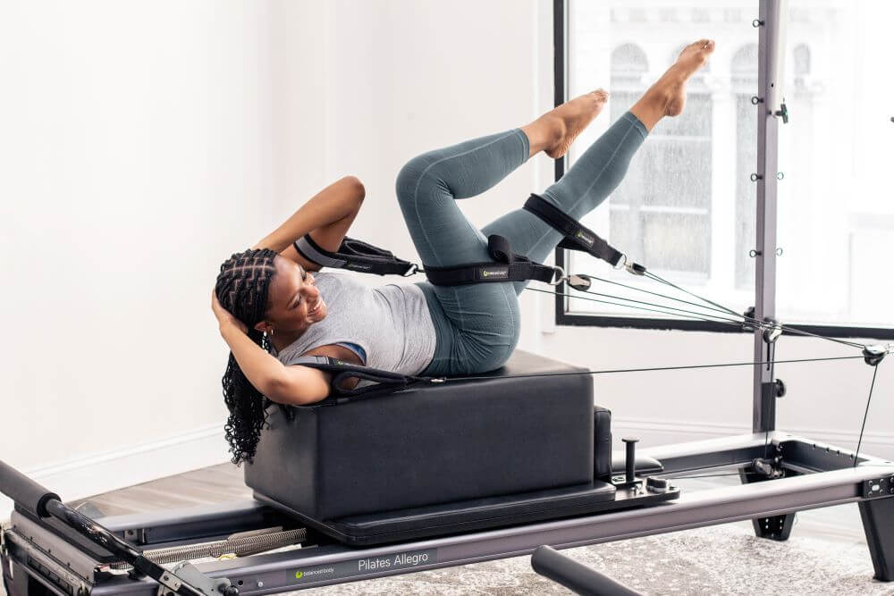 Person exercising on Allegro Reformer Konnector in studio setting.