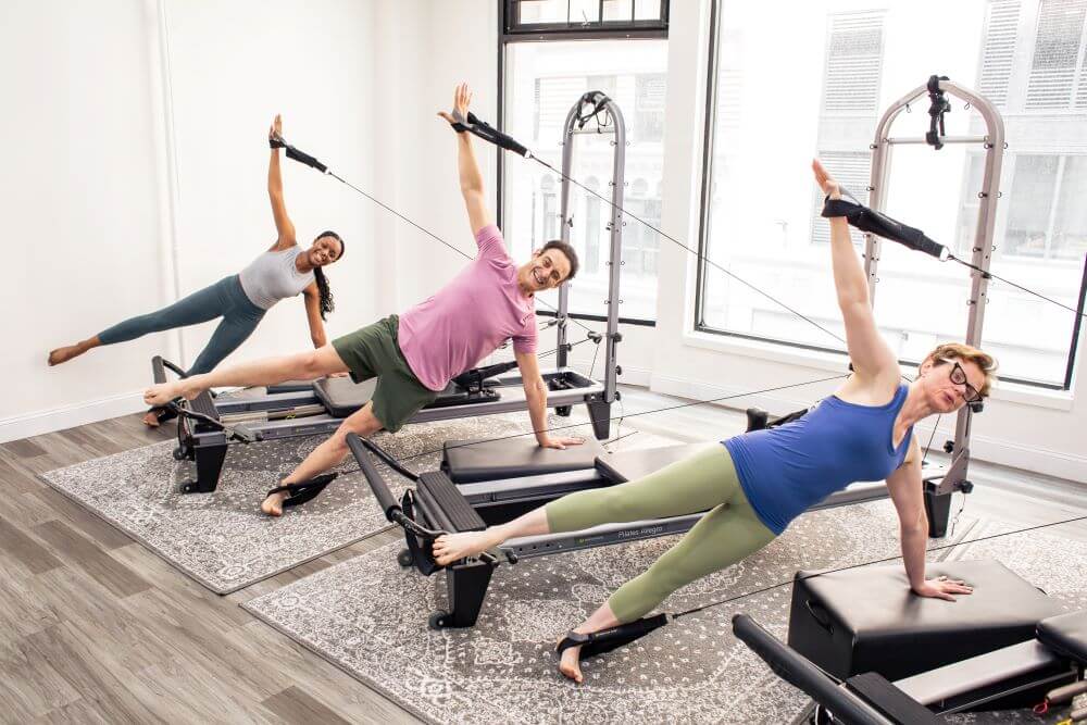 People exercising on Allegro Reformer Konnector in a studio.
