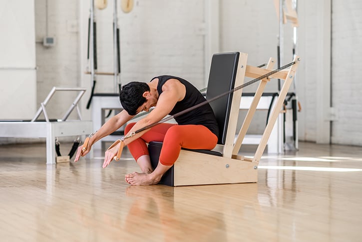 Instructor demonstrating exercise on Contrology Arm Chair in studio.