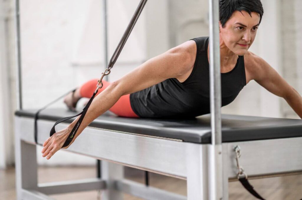 Person using Contrology Cadillac JPack Springs for arm exercise.