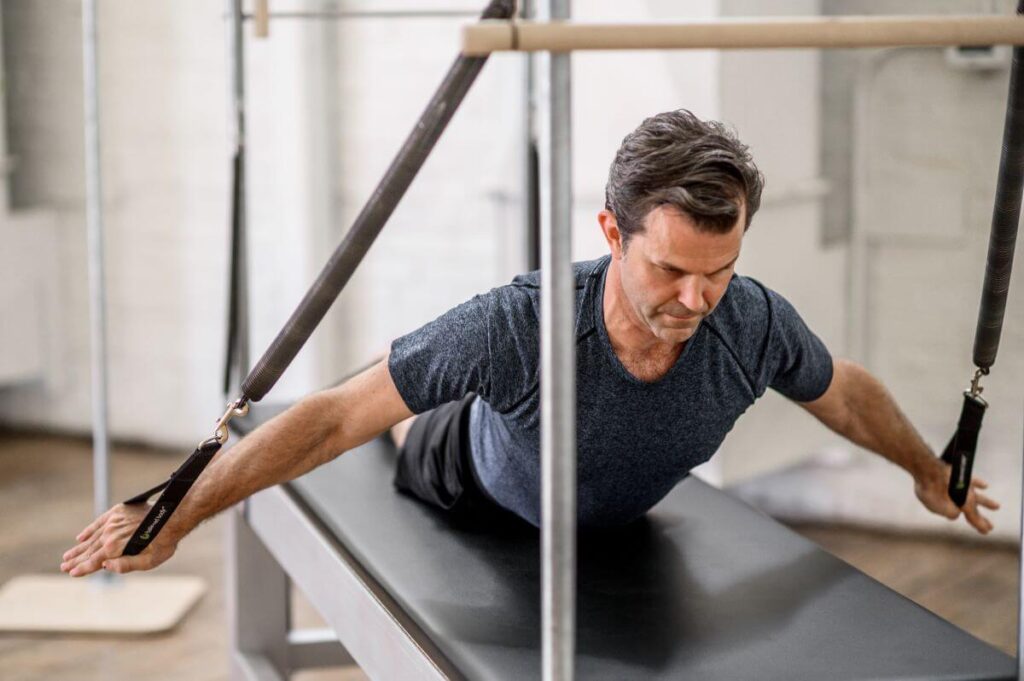 Man using Contrology Cadillac JPack Springs for Pilates exercise