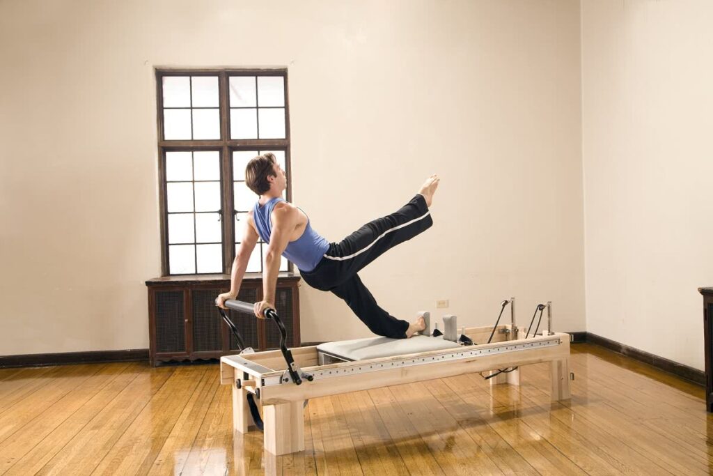 Person exercising on Clinical Reformer in a bright room.
