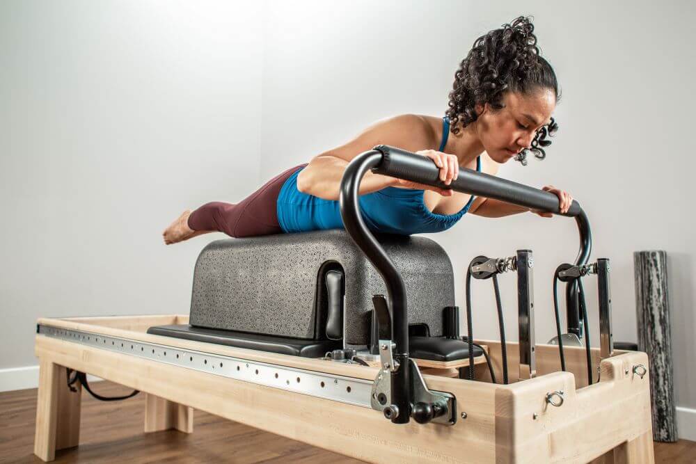 Woman exercising on Balanced Body Clinical Reformer in studio.