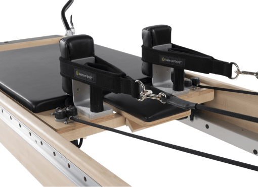 Pilates carriage with black padding, adjustable headrest, and TwistLock shoulder rests.