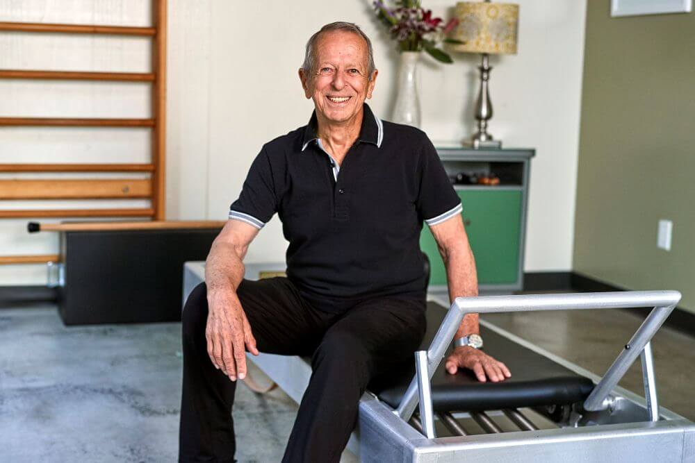 Man sitting on Contrology Reformer in Pilates studio.