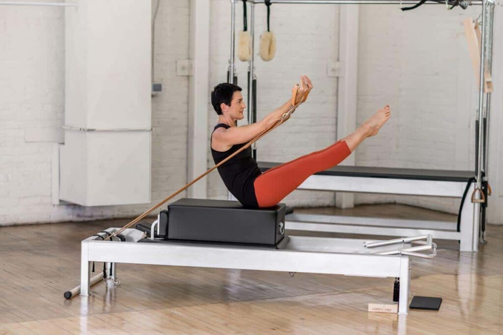 Person performing Pilates seated exercise on Contrology Box.