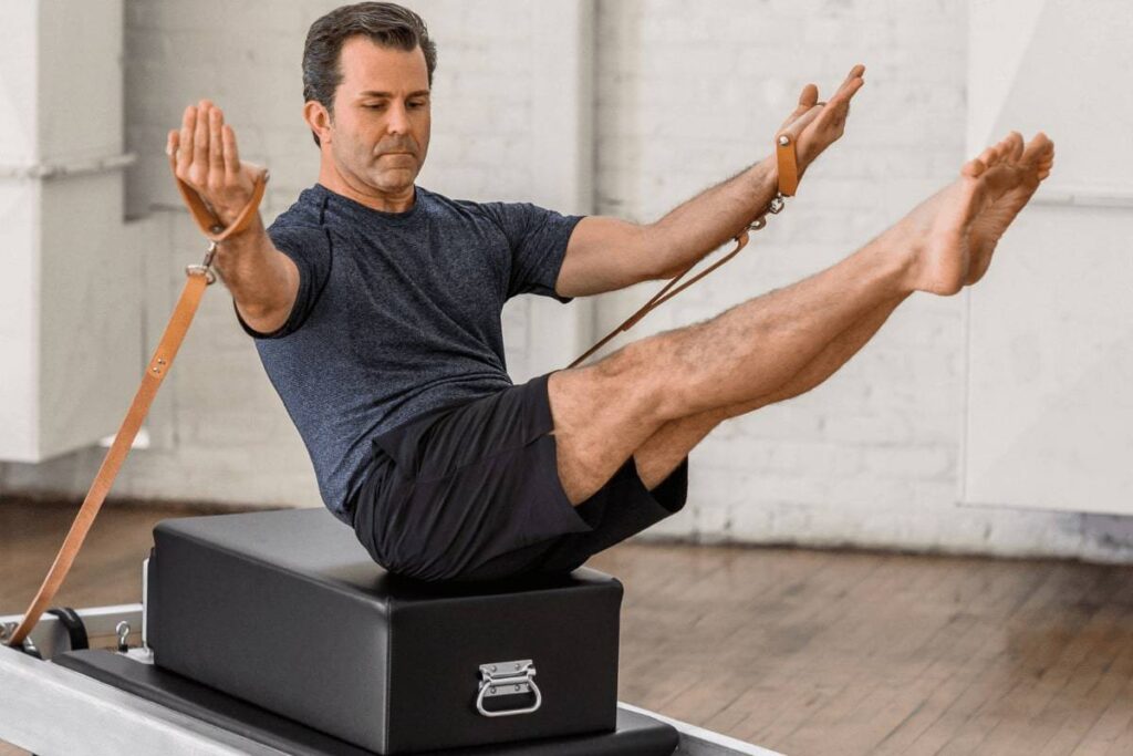 Man performing Pilates on Contrology Box with straps.
