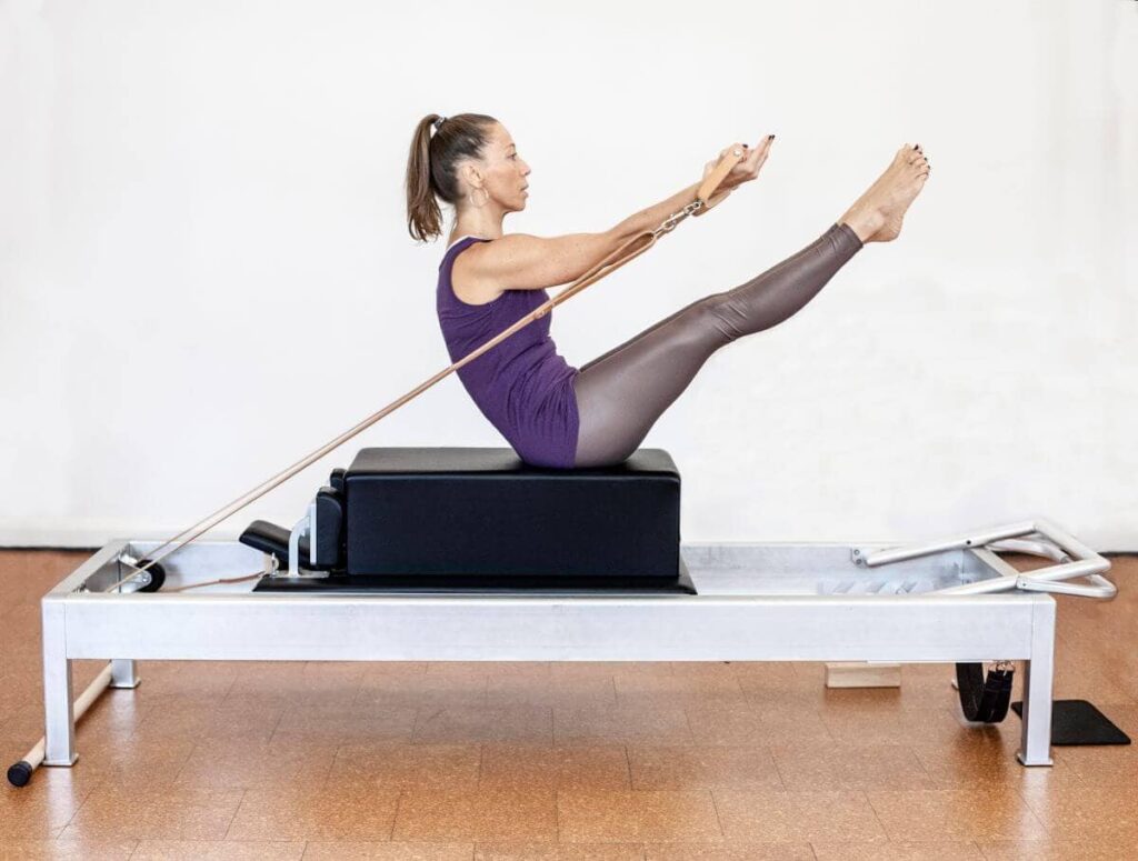 Woman using Contrology Leather Handles on a Pilates reformer