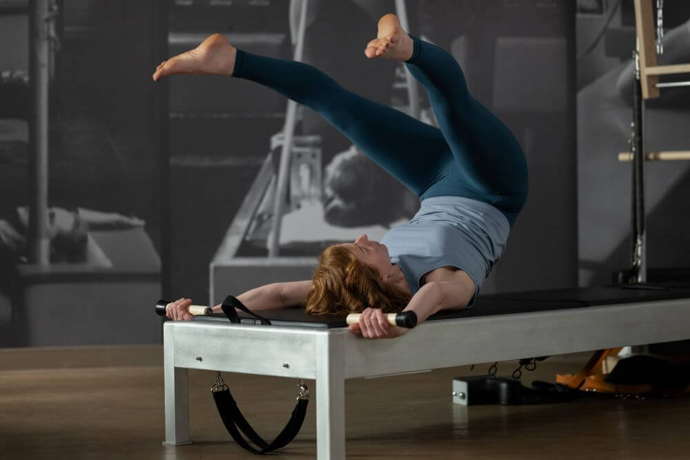 Woman exercising on Contrology Reformer with Tower and Mat