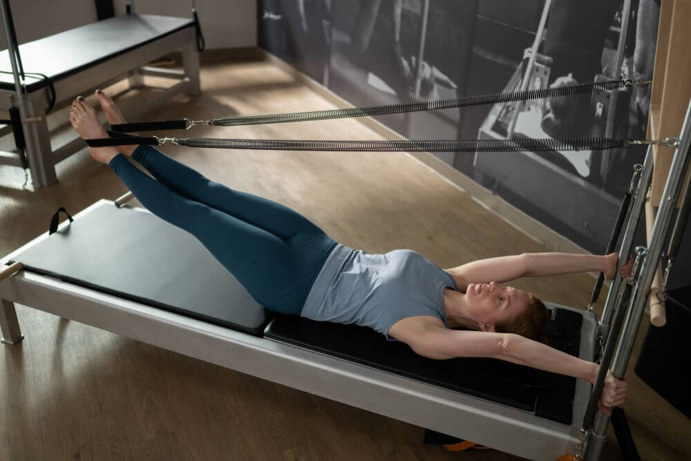 Person exercising on Contrology Reformer with Tower and Mat.
