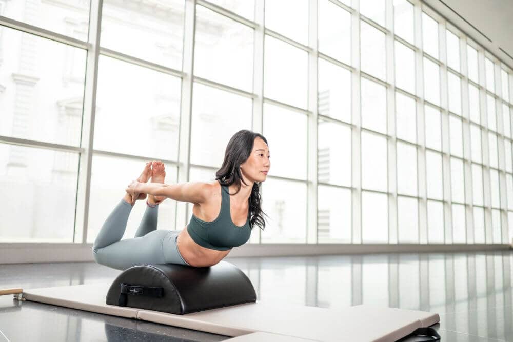 Woman exercising on Contrology Small Barrel in bright studio.