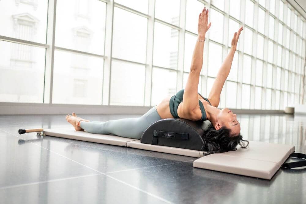 Woman exercising on Contrology Small Barrel during Pilates.