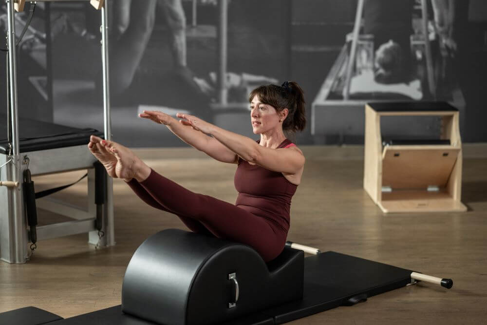Woman exercising on Contrology Spine Corrector in Pilates studio.