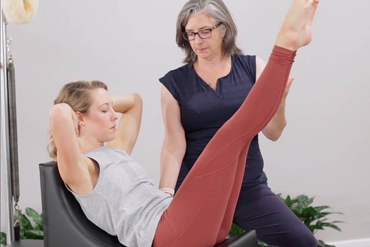 Instructor assisting Pilates exercise on C-Shaper.