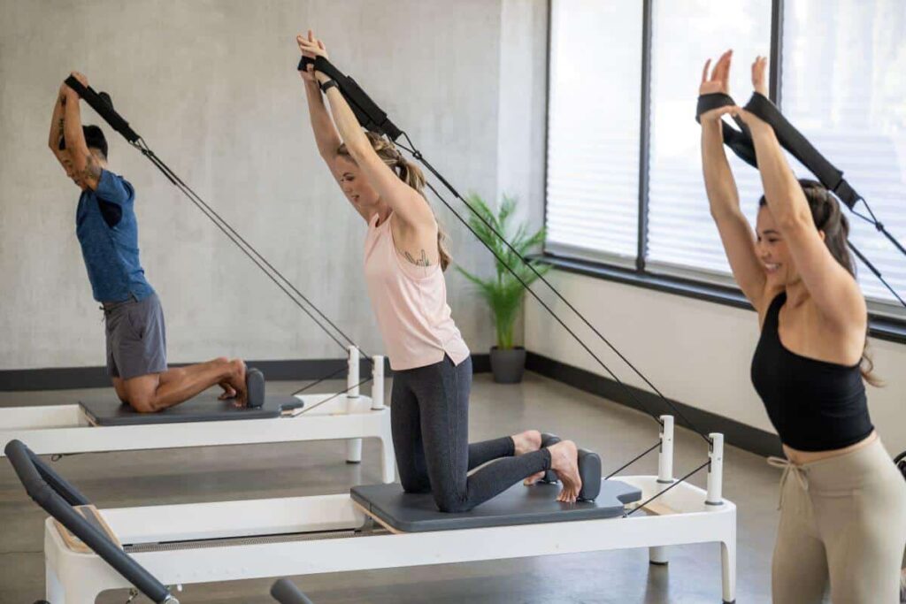 Pilates practitioners using Double Loops on reformers in a studio.
