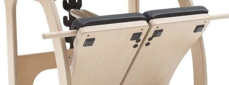 Pilates equipment with split footstep design and non-slip padding.