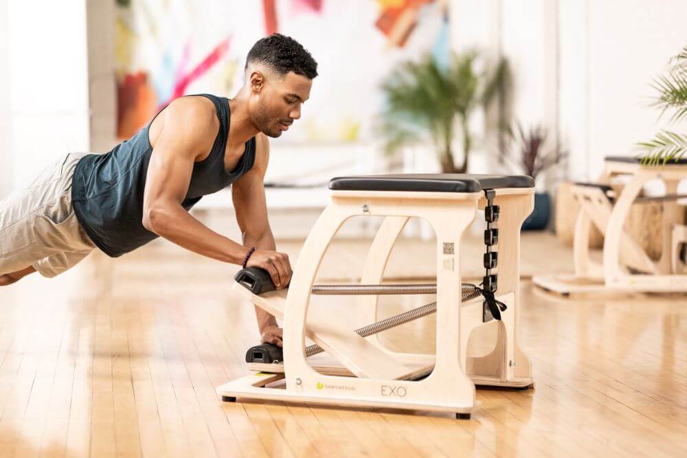 Man exercising with EXO Chair in a studio setting.