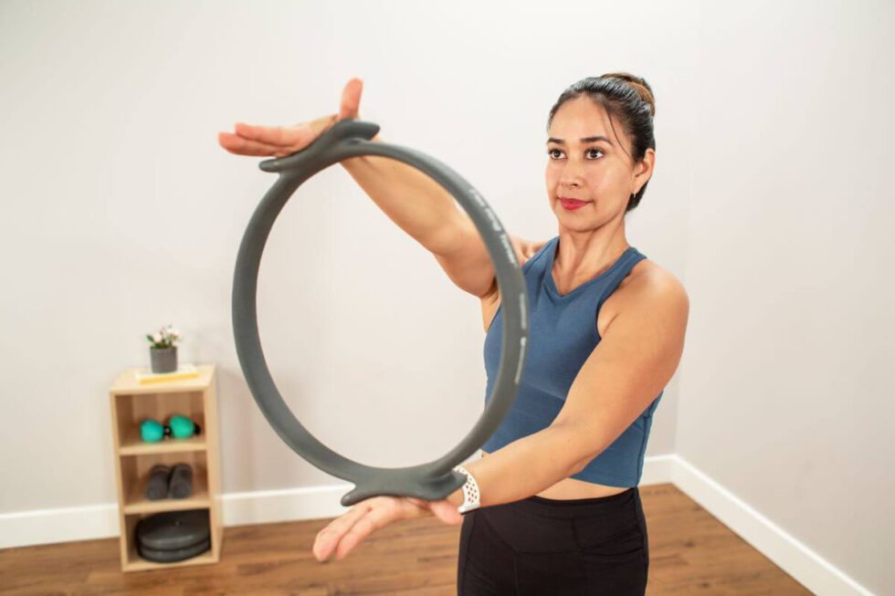 Woman demonstrating Flex Ring Toner exercise in studio.