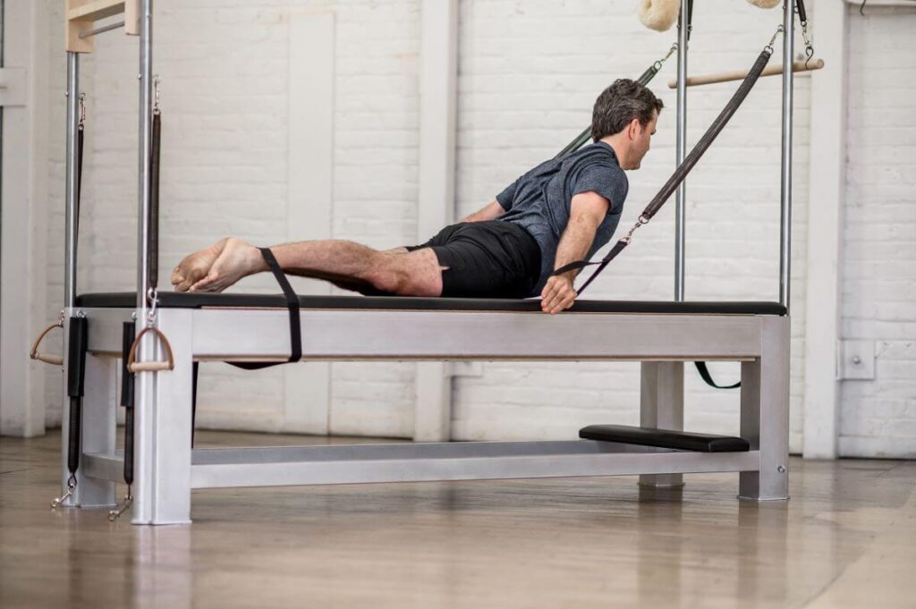 Man using Contrology Cadillac JPack Springs for Pilates exercise.