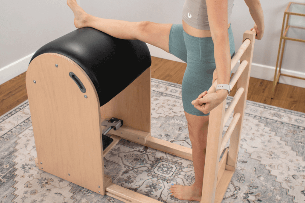 Person using Balanced Body Ladder Barrel for Pilates stretching.