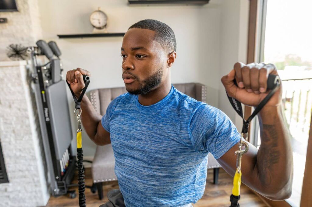 Man exercising with Balanced Body Neoprene Handles at home.