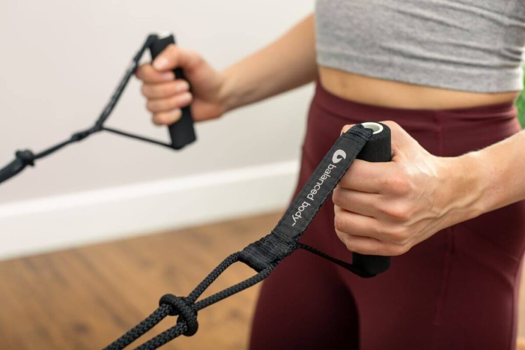 Close-up of hands holding Balanced Body Neoprene Handles for Pilates.