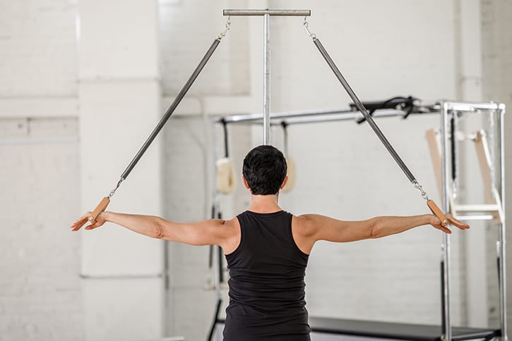 Person using Contrology Ped-o-Pul in Pilates studio for stability exercises.