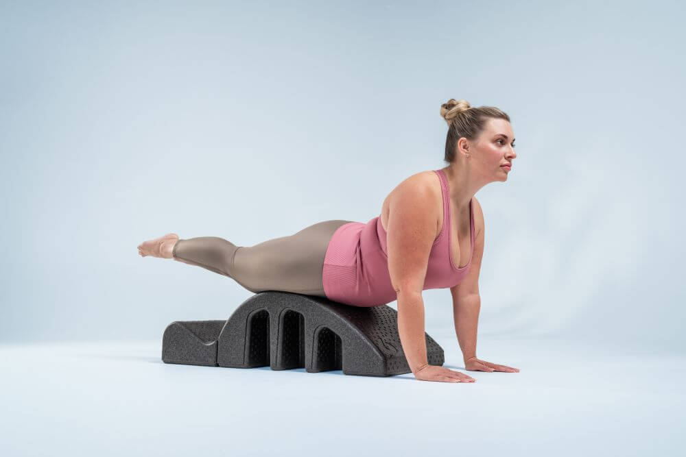 Woman performing exercise on Pilates Arc for spine strengthening.