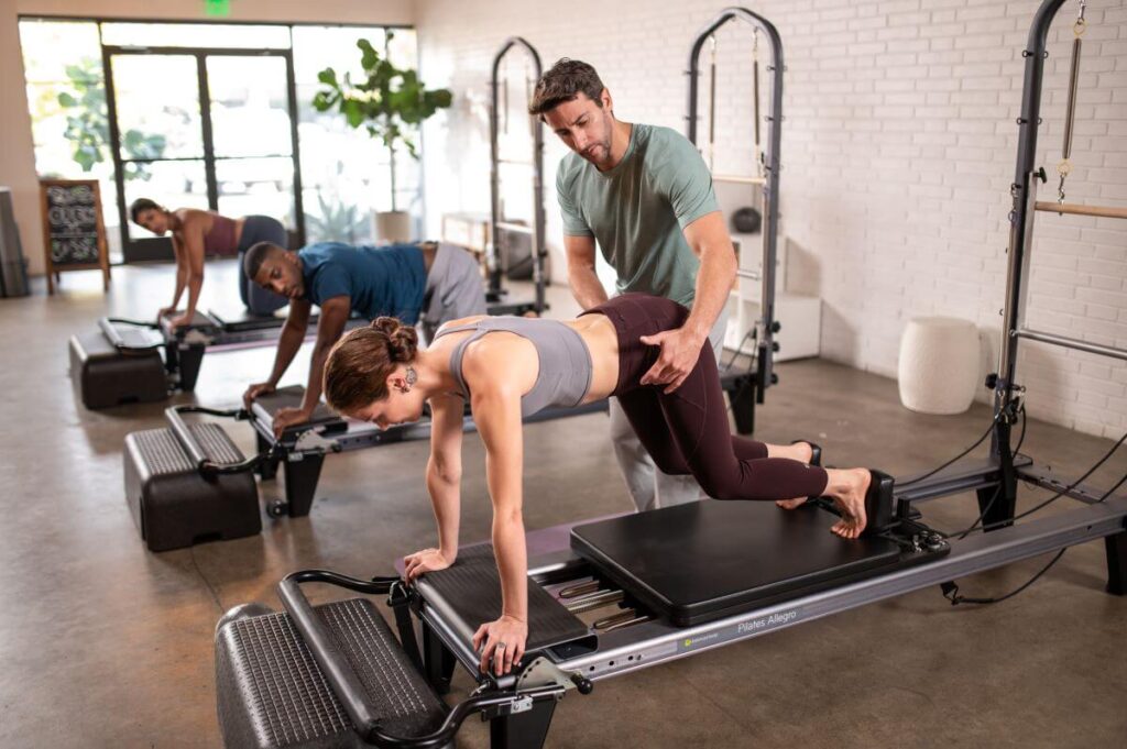 Pilates instructor assisting on Allegro Reformer with Platform Extender.