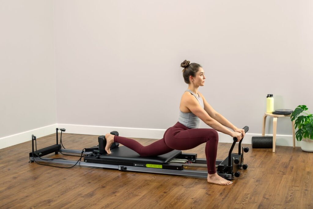 Woman exercising on Metro IQ Reformer in a home setting.
