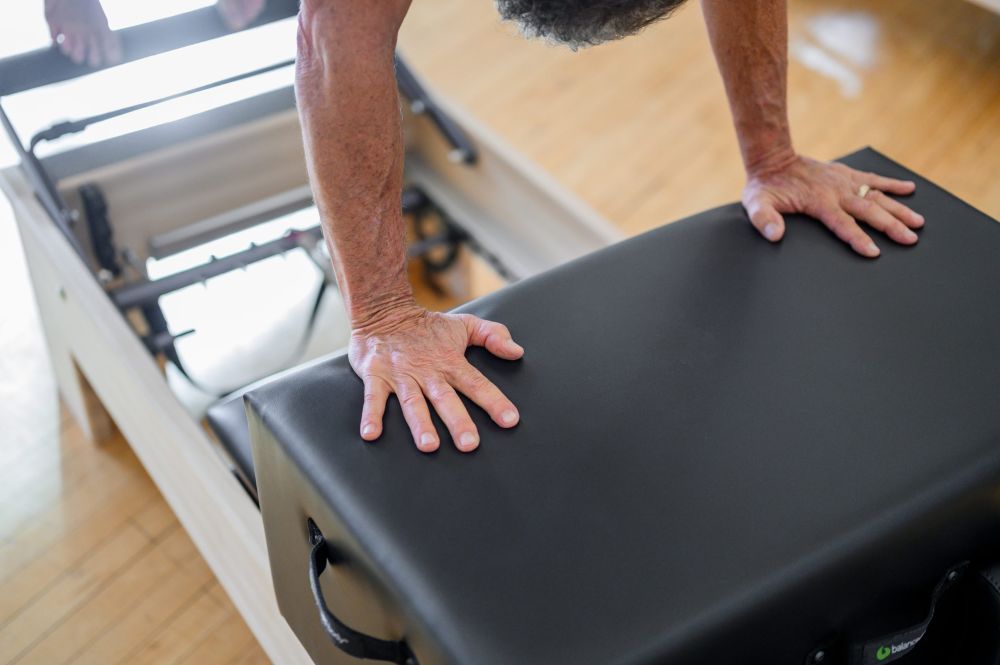 Person using New York Sitting Box on Pilates Reformer.