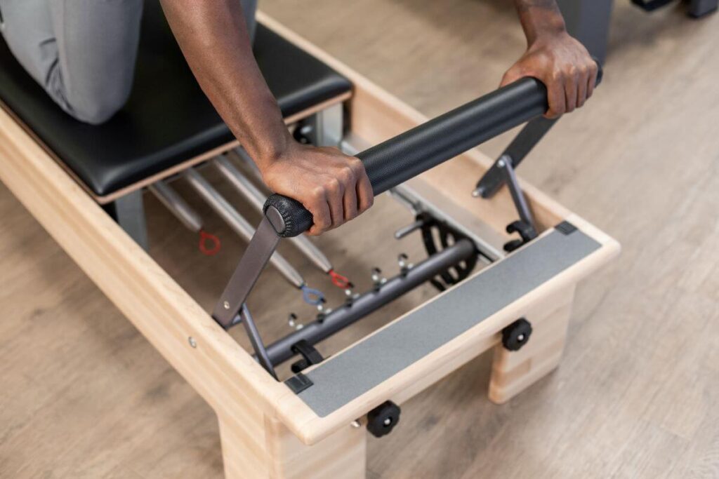 Person adjusting Reformer Signature Springs on Pilates machine.