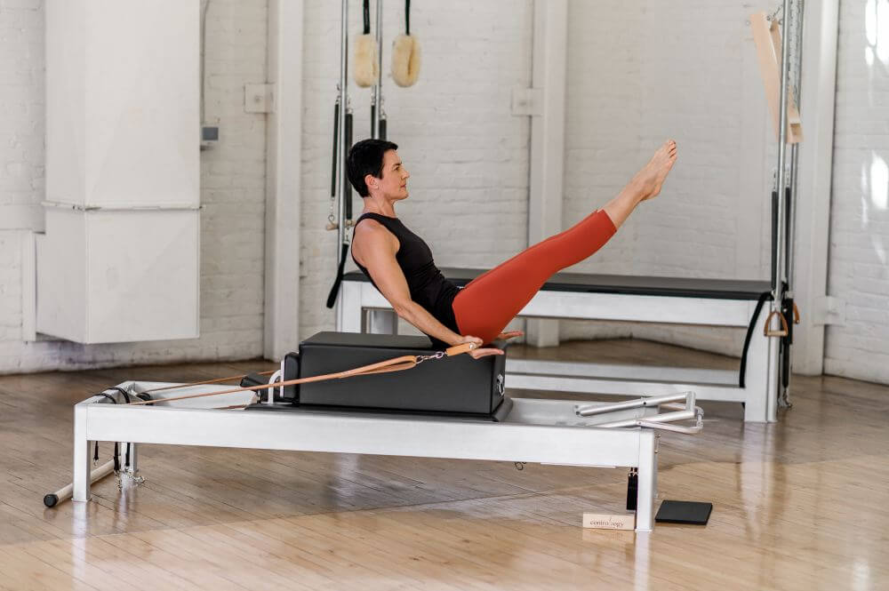 Person exercising on Contrology Reformer in a Pilates studio.