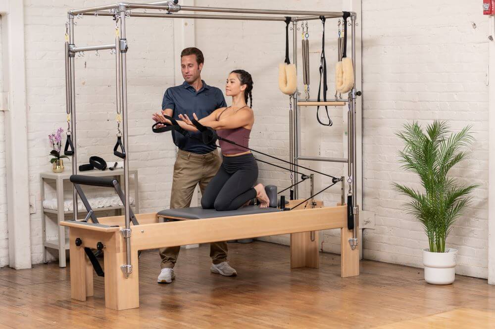 Instructor assisting client on Reformer Trapeze Combination.