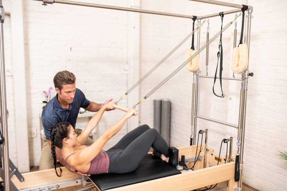 Instructor assisting client on Reformer Trapeze Combination.