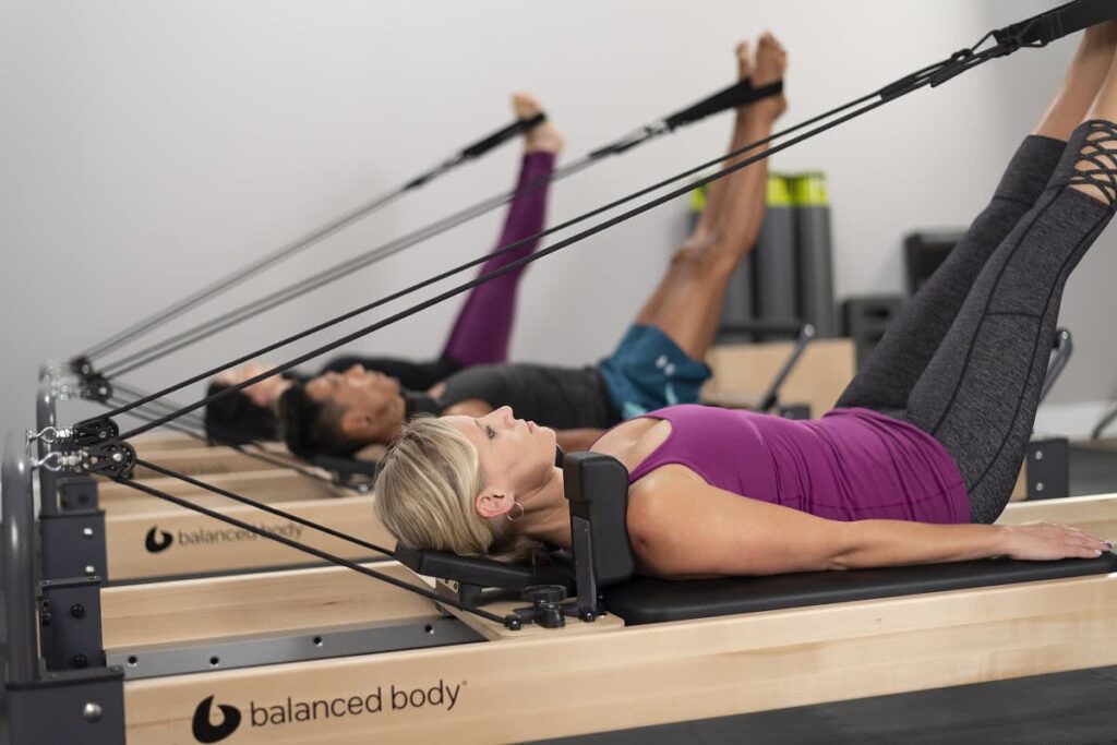 Instructors using Balanced Body Studio Reformer for Pilates.
