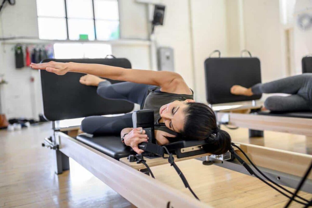 Person exercising on Rialto Reformer Jumpboard in Pilates studio.