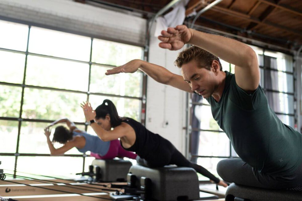 Pilates class using Sitting Box Lite on reformers in a studio.