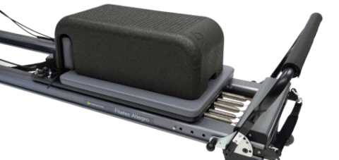 Lightweight black Pilates box with textured surface on reformer.