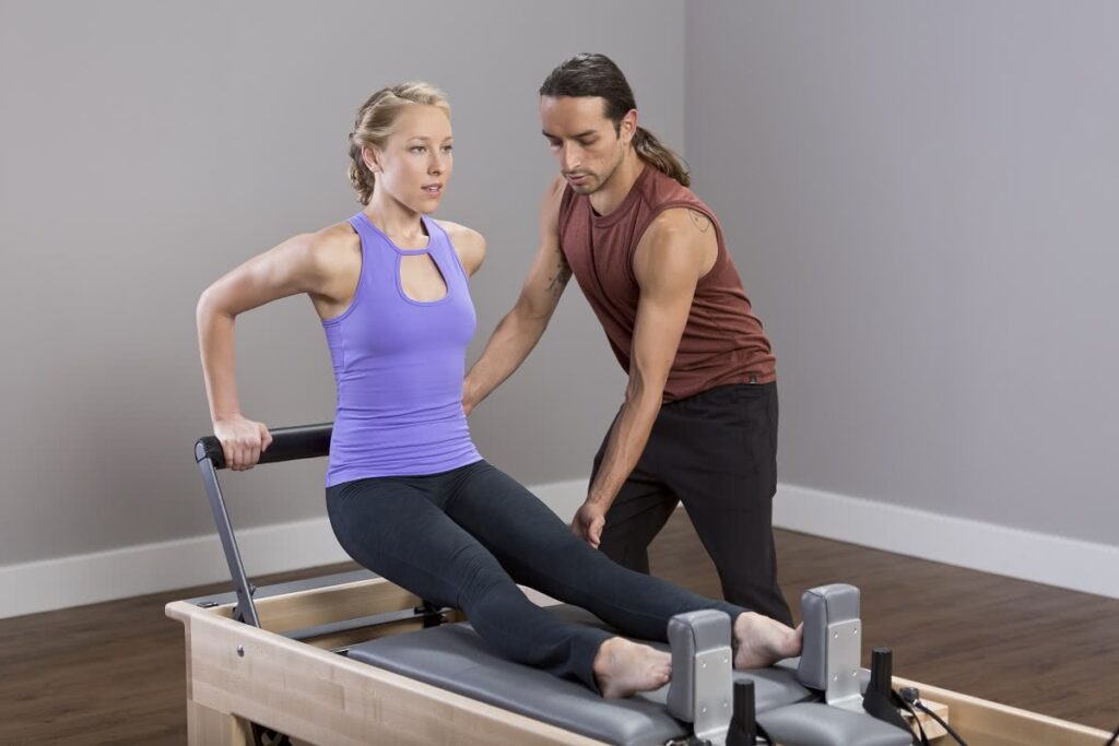 Instructor assisting woman on Studio Reformer with Tower.