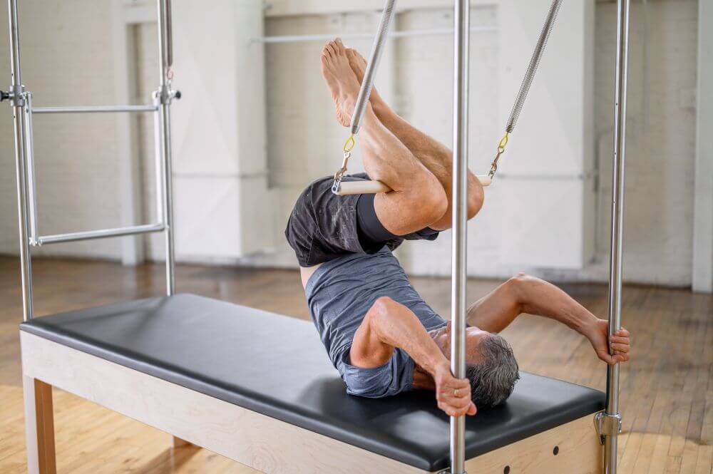 Pilates Trapeze Table demonstration with user exercising on Cadillac.
