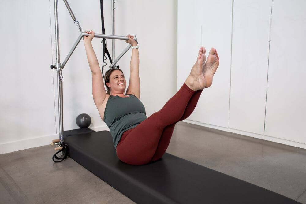 Woman exercising on Wall Tower with Pilates mat support.