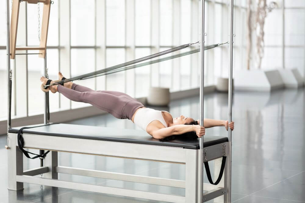 Pilates exercise using Contrology Airplane Board on Cadillac.