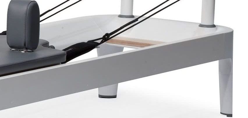 Pilates equipment frame with adjustable legs and maple platform.