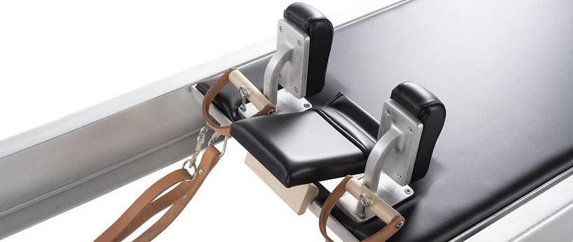 Pilates reformer carriage with smooth ride and black padding.