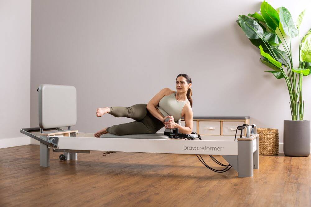 Woman using Bravo Reformer Jumpboard in Pilates studio.
