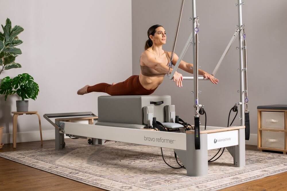 Woman performing an exercise on the Bravo Reformer with Tower.